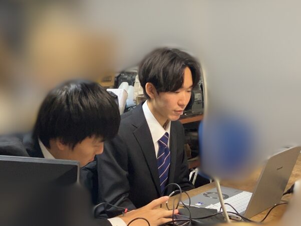 2人の学生がPCを見ながら打ち合わせを行っています