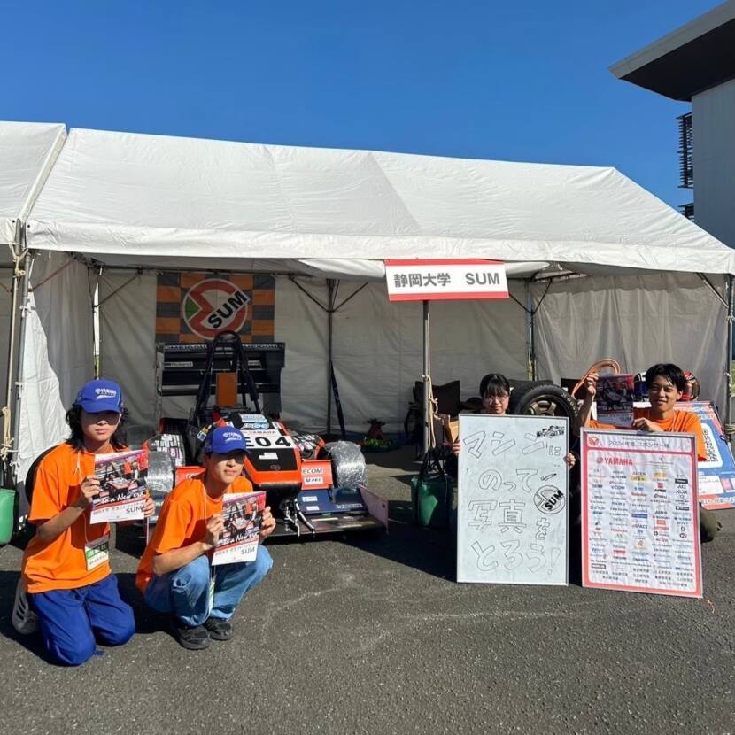 マシンの前でメンバーがビラやパネルを掲げている様子